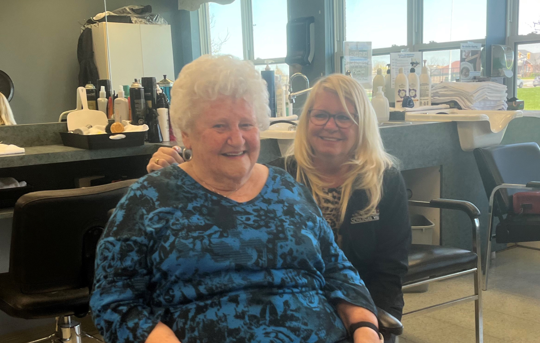 Donna and Debbie sit together on the salon, bright and smiley.