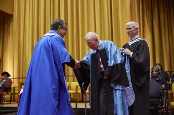 Alan Tomlinson on stage shaking hands with the president of the University of Waterloo
