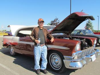 Aspen Lake resident Dan Kinney standing in front of his red '56 Chevy Bel Air in a parking lot
