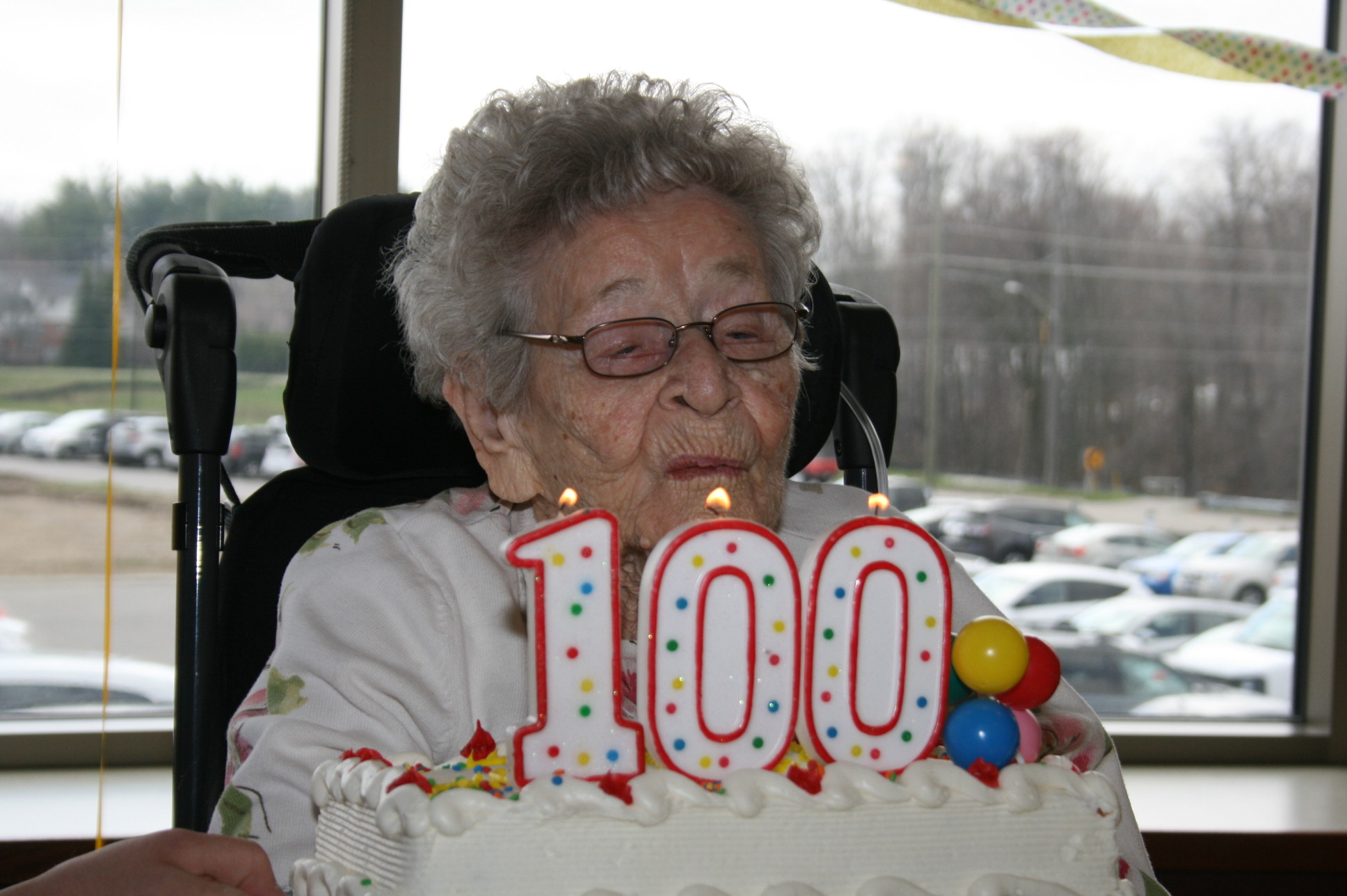 Dot blowing out candles that day 100 on her birthday cake