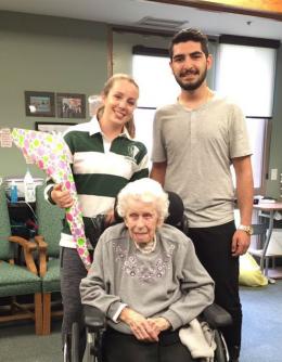Co-op student Laura holding a bouquet of flower, with her future prom date Ramtin, standing behind resident Laura who is sitting in her wheelchair