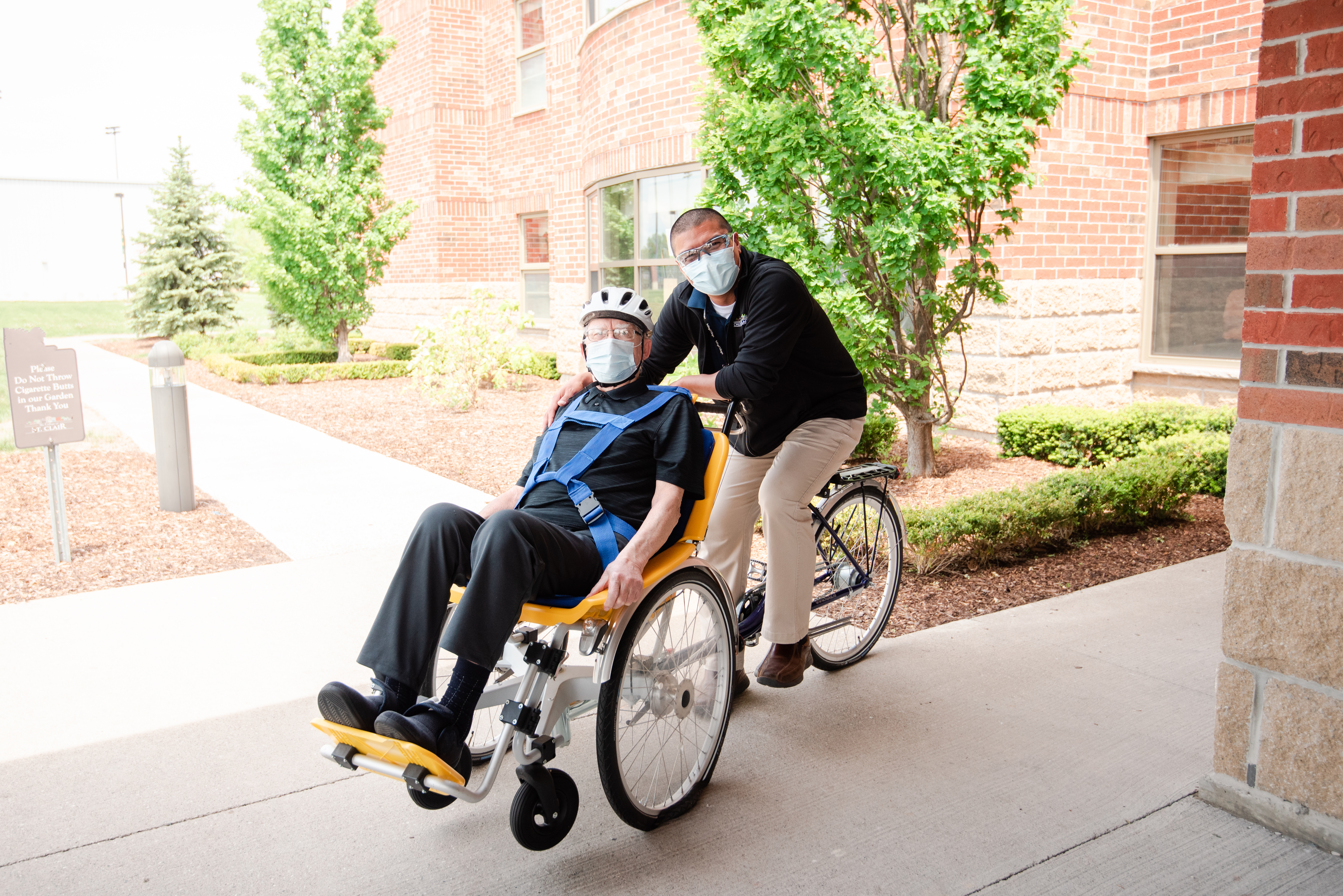 Schlegel Villages team member takes senior on duet bike for a ride outside the village