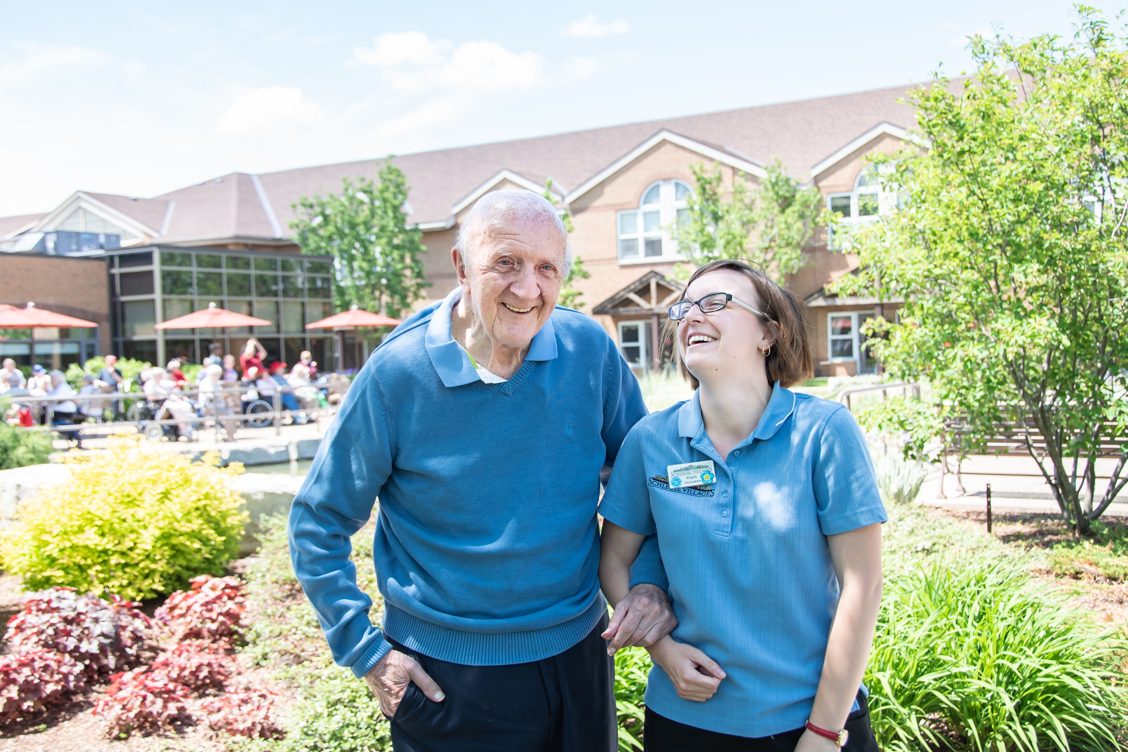 Schlegel Villages team member laughing with senior by the courtyard pond