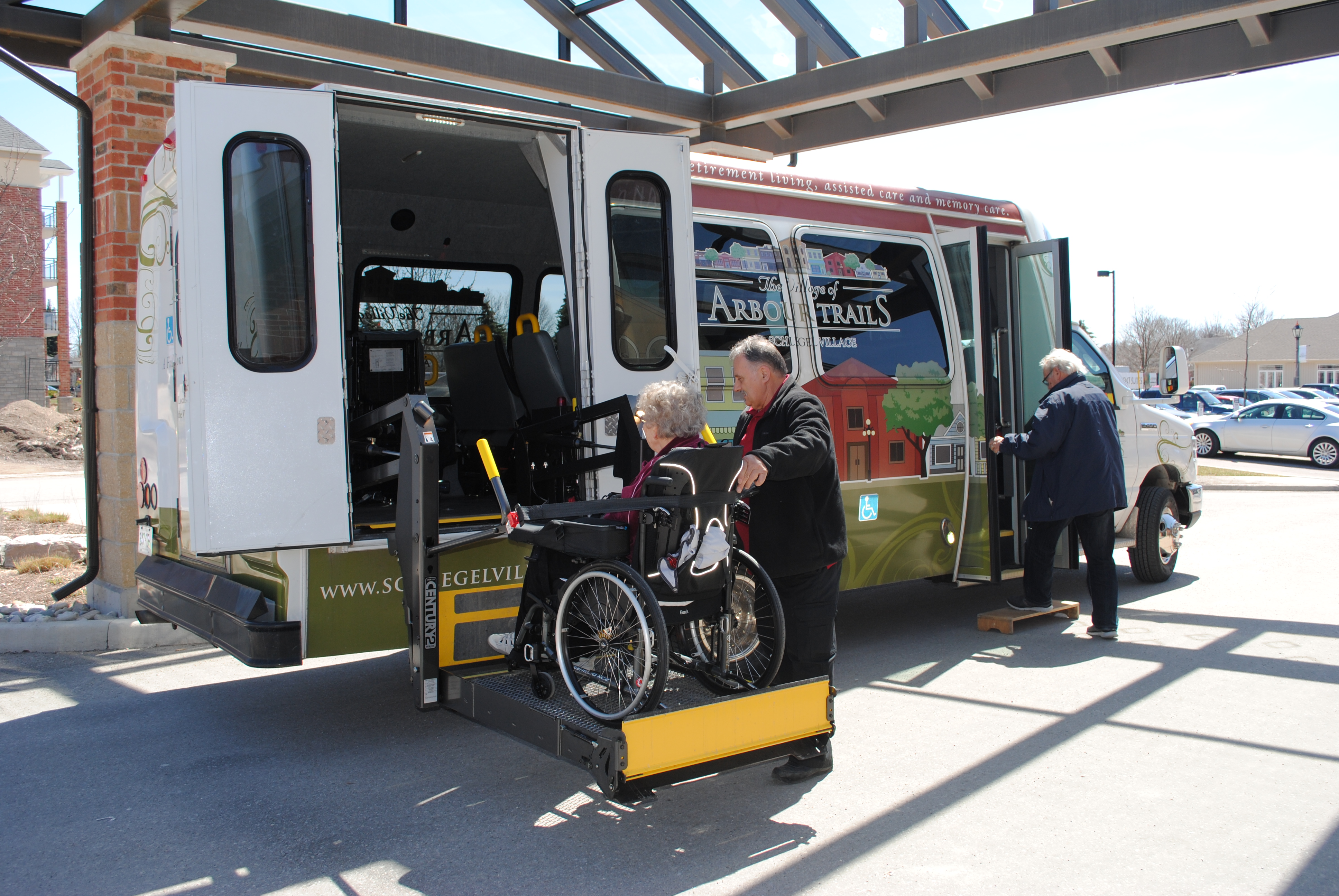 Village shuttle driver helping a resident in a wheelchair onboard