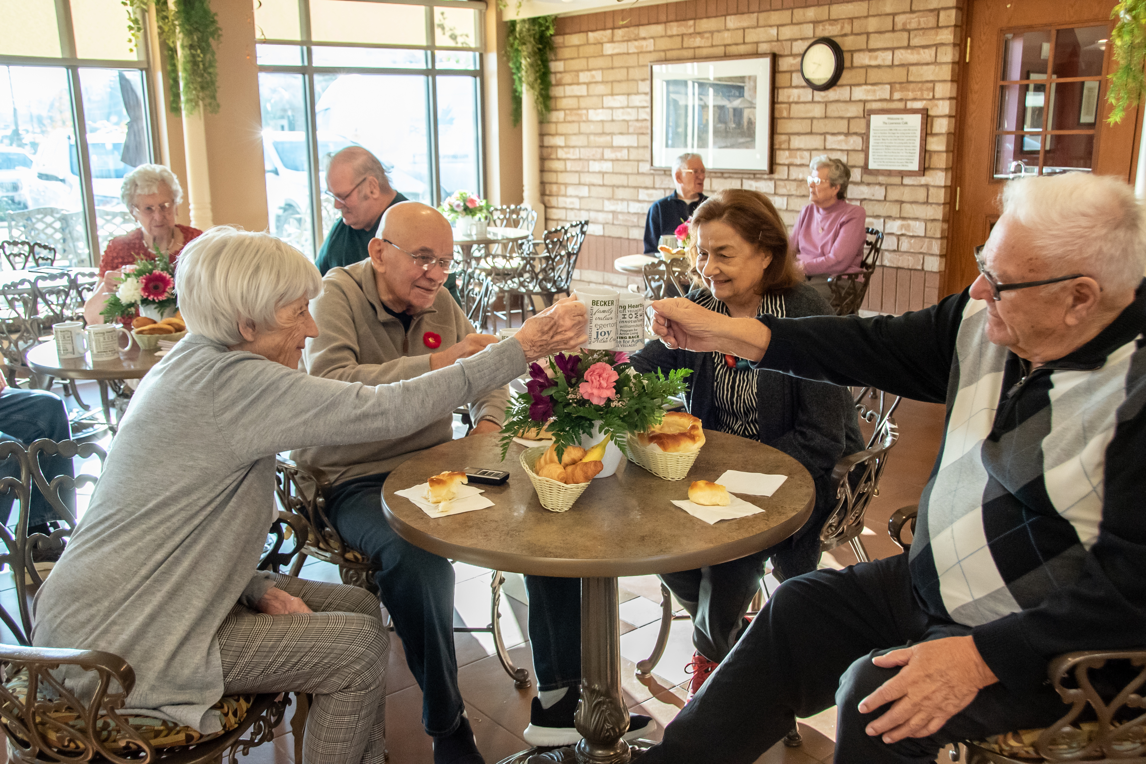 Group of residents toasting with their coffee mugs in the Village cafe.