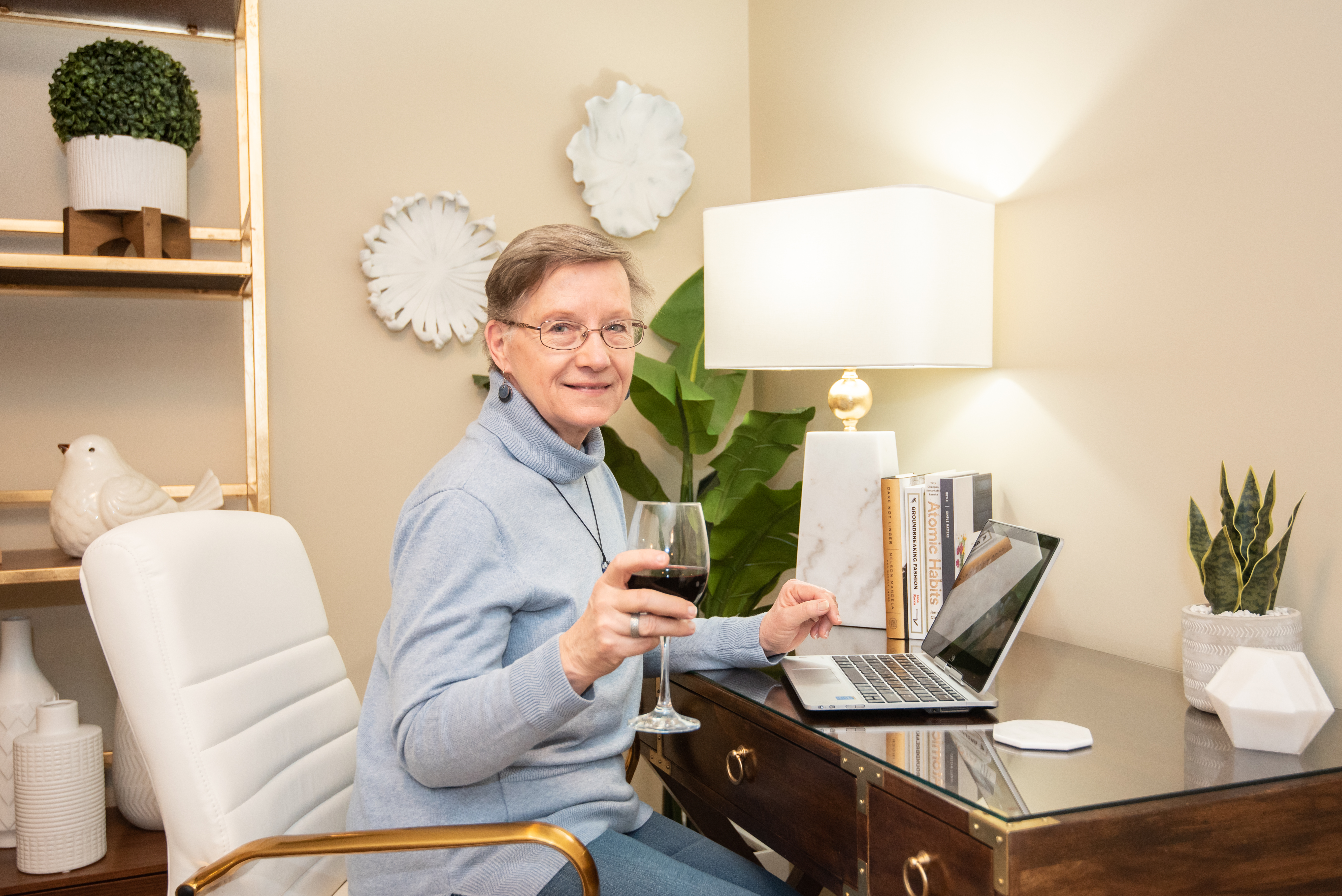 Resident enjoying a glass of wine in her Independent Living apartment at her desk