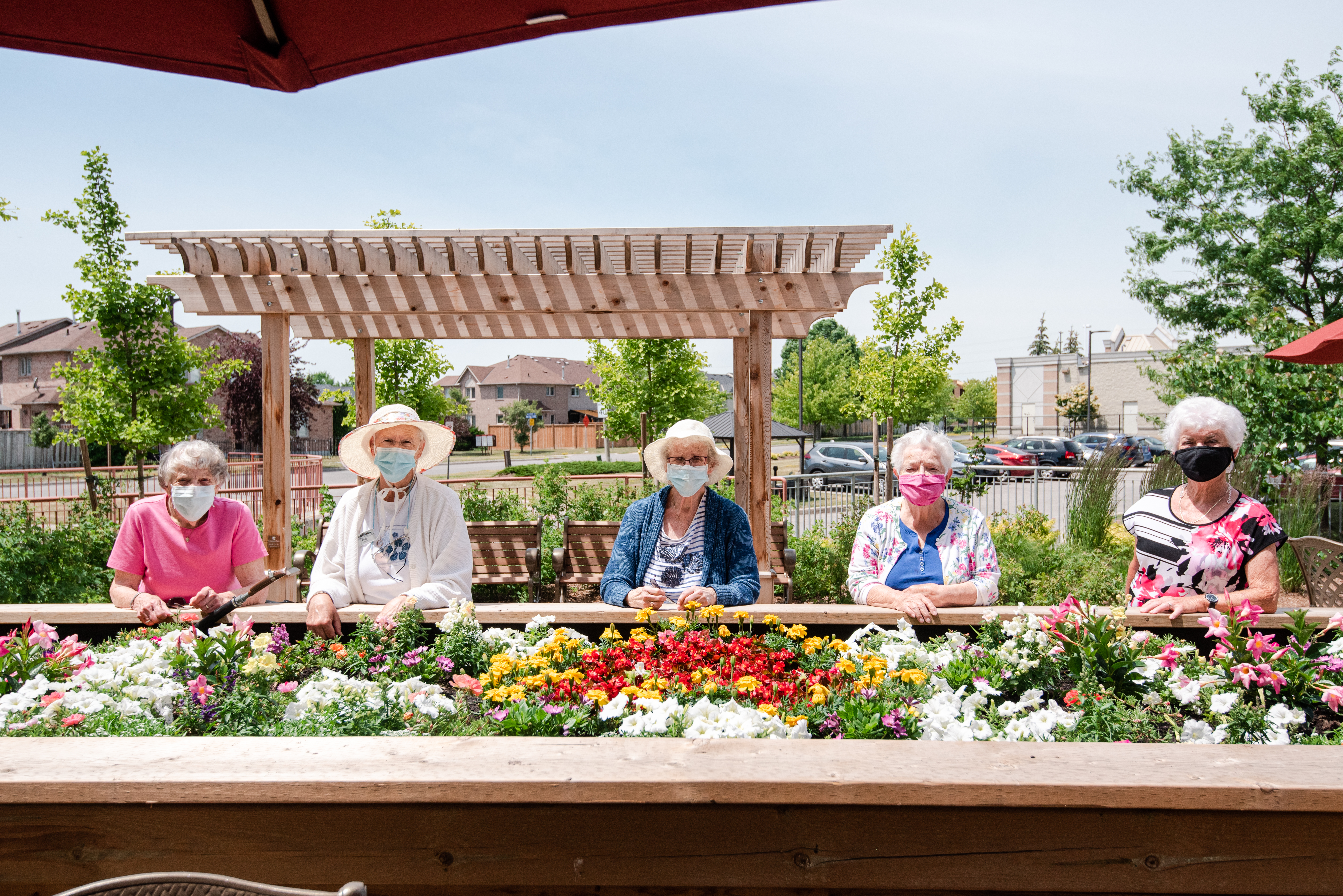 Five residents showcase the flowers they planted in the village raised garden bed