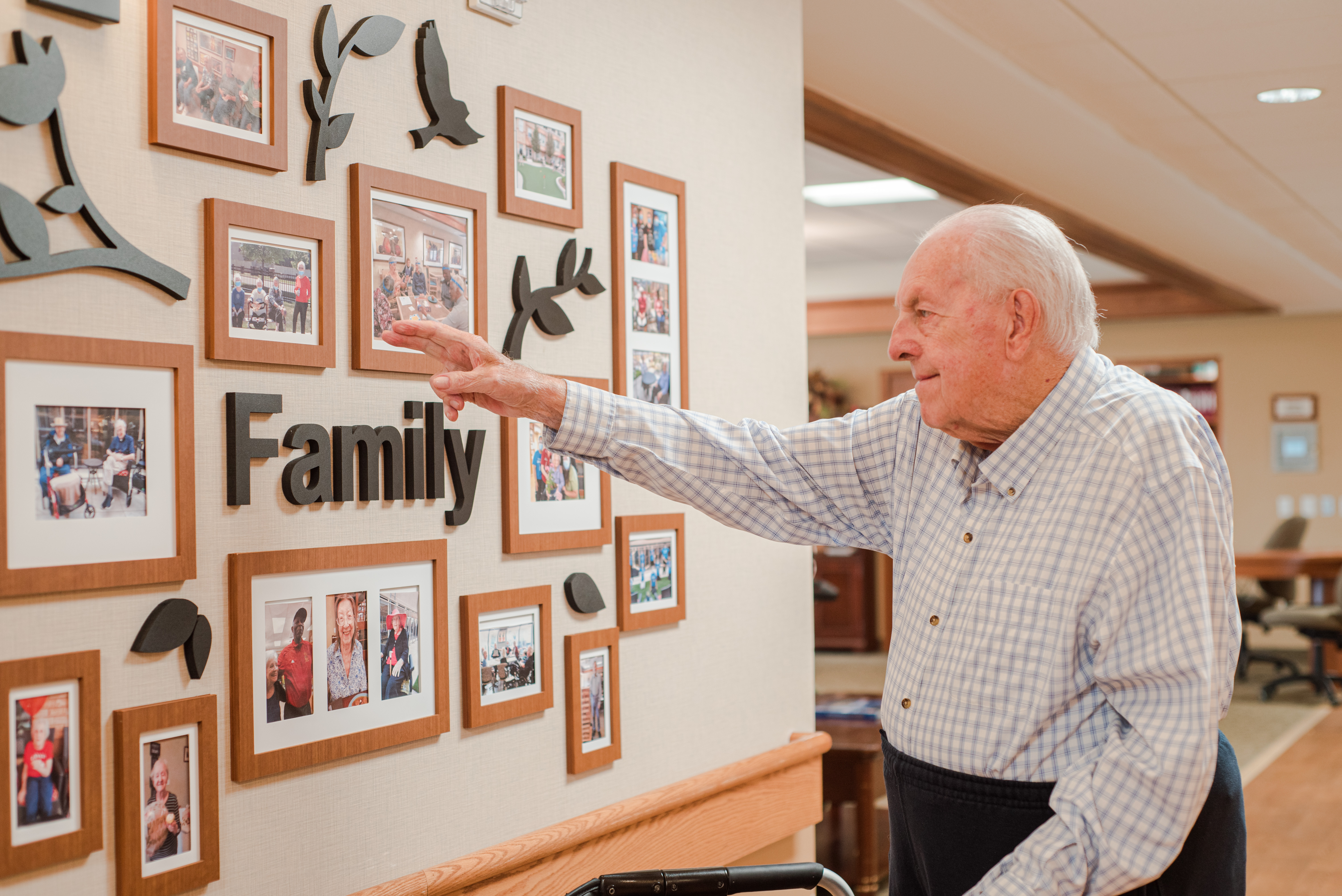senior man looking at the wall of portraits with the word Family in the middle