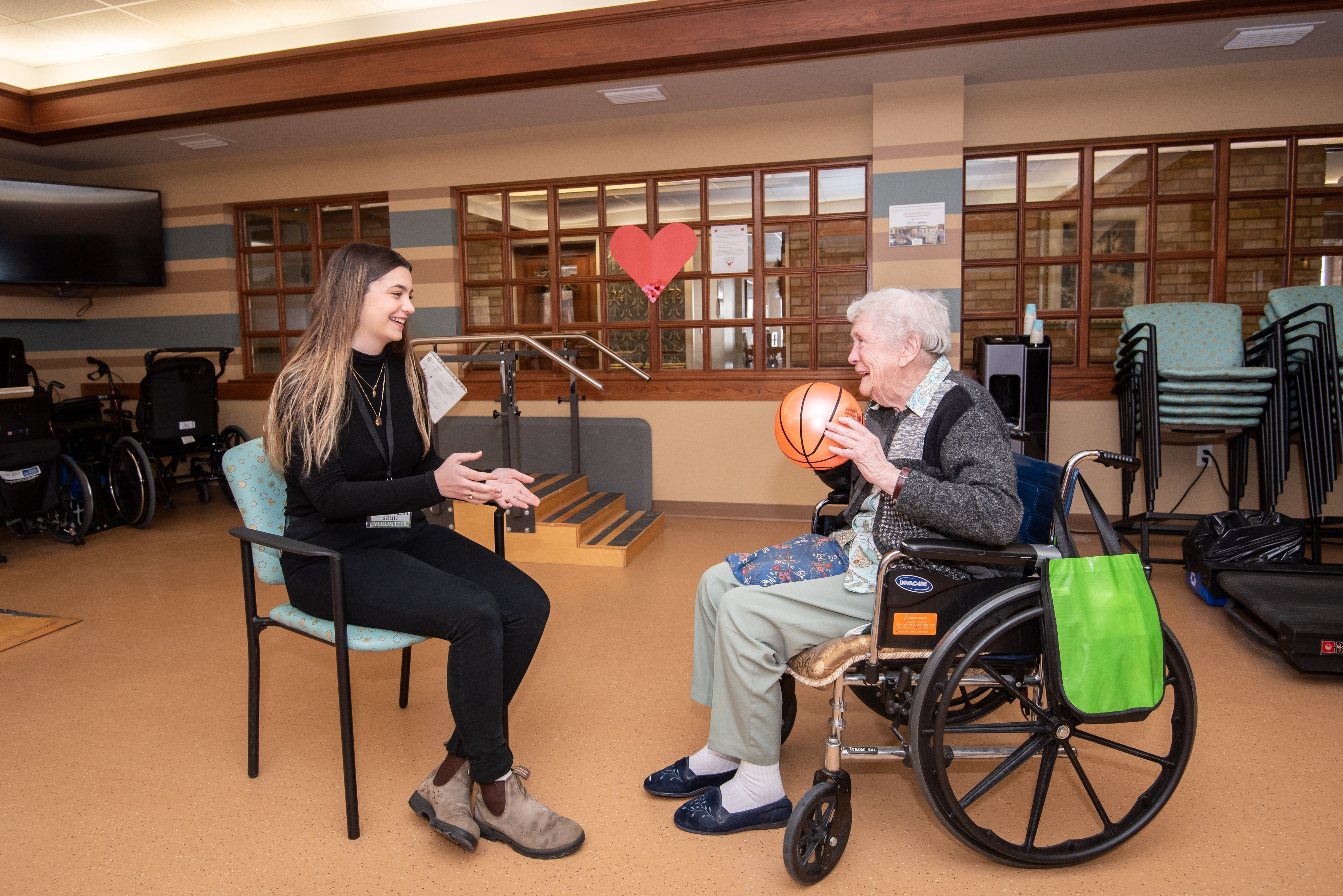 Student participates in the Program for Active Living with a senior passing a ball