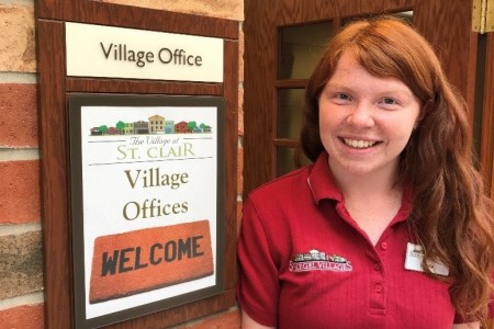 Natalie poses with the Village Office sign at The Village at St. Clair