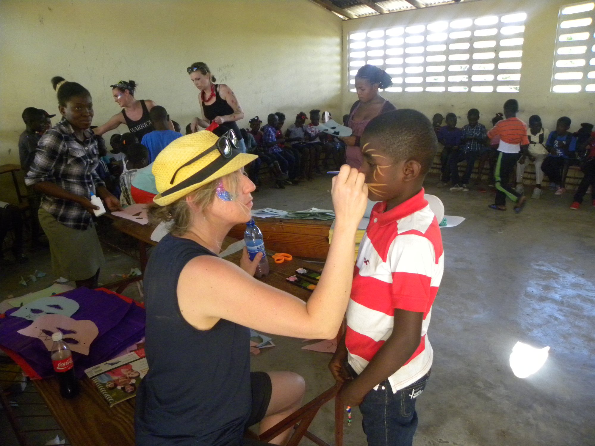 Team Member painting a Haitian child's face while volunteering in Haiti