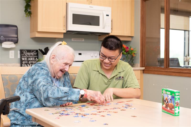 Team member supporting resident while completing a jigsaw puzzle
