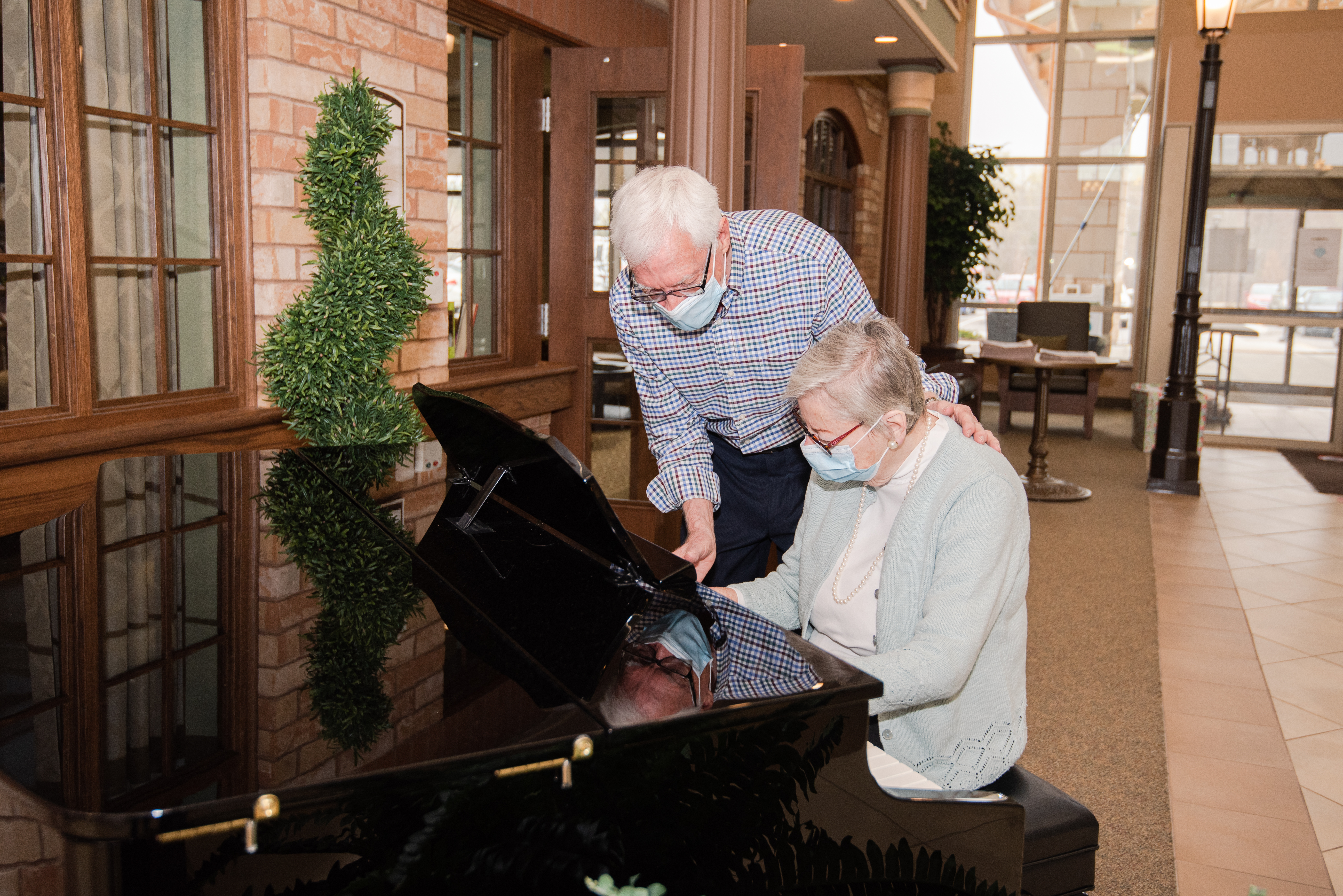 Senior man encouraging his wife to play the piano in the town square at the Village
