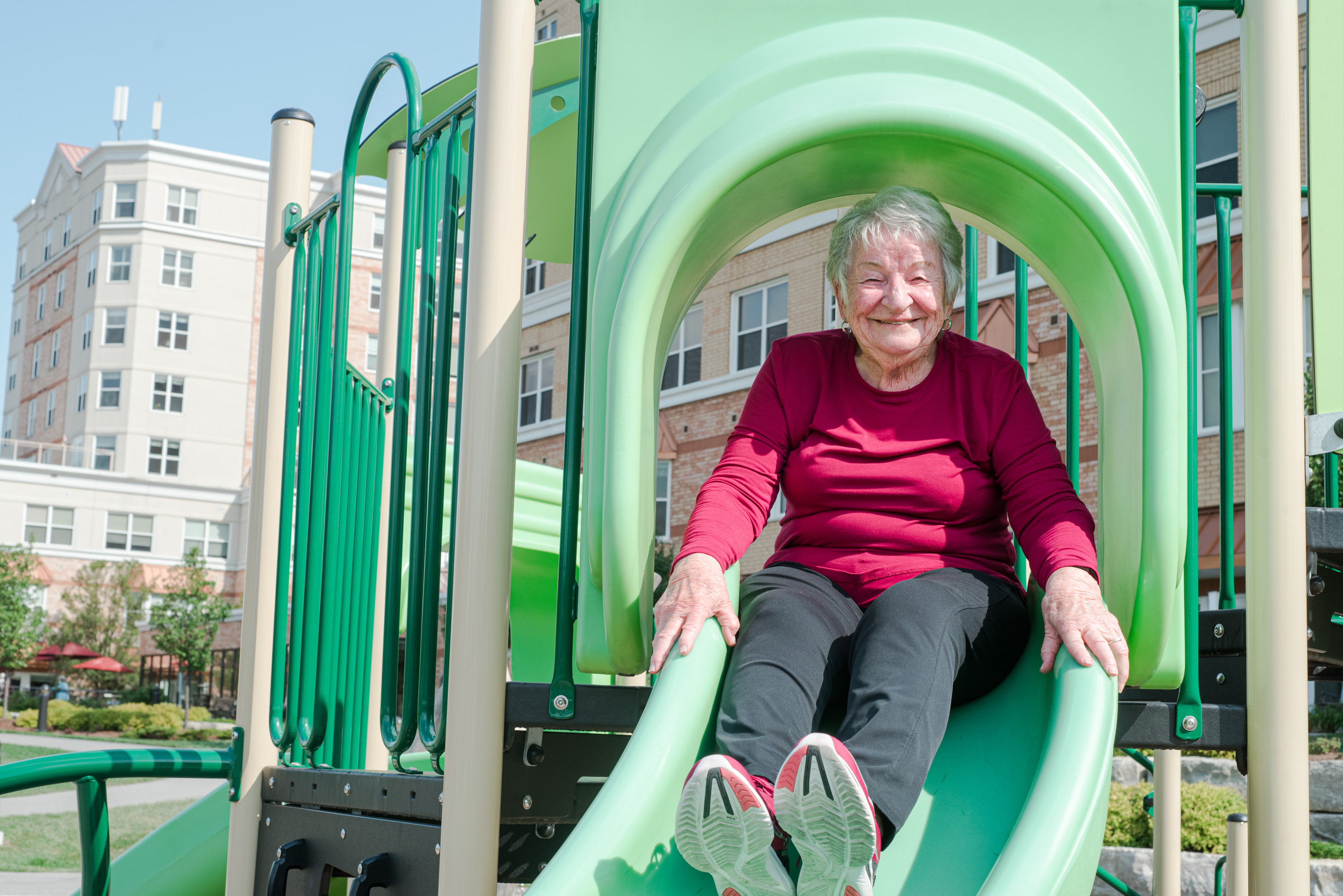 Resident sliding down slide in The Village of Taunton Mills playground