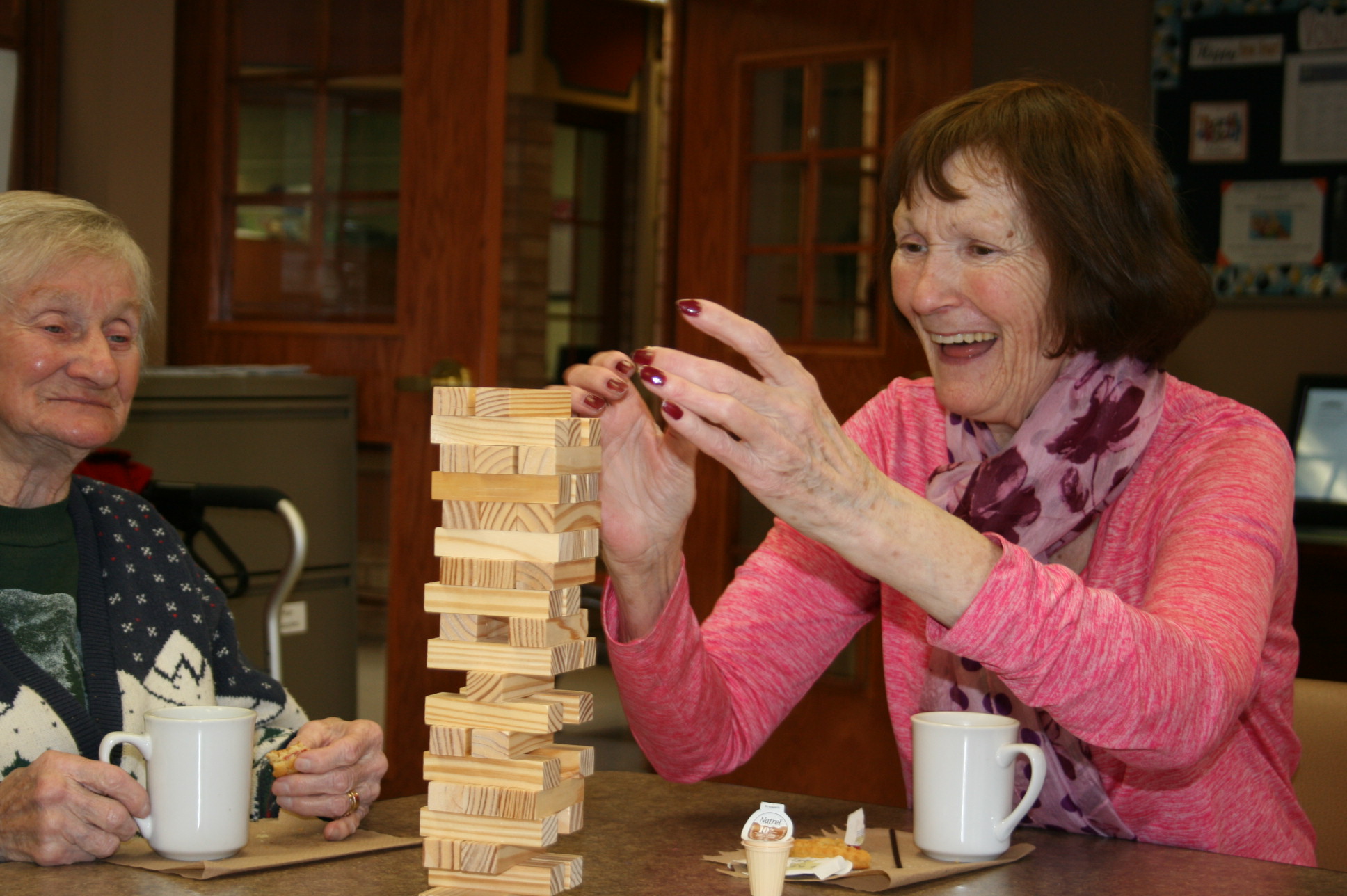 Visitor laughing and playing Jenga with a resident