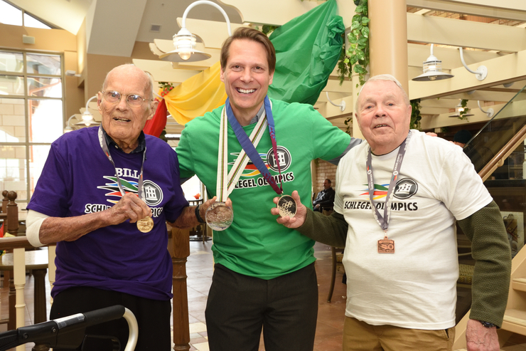 Brad Schlegel, who won two silver medals for Team Canada in hockey at the 1992 and 1994 Olympics, stands with two residents who won medals at the Schlegel Olympics.
