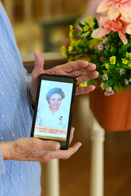 Ursula holding a cell phone with a photo of herself as a nurse