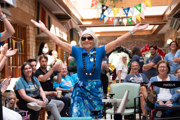 A resident is pictured during the Olympics with her arms outstretched widely and a wide smile upon her face. 