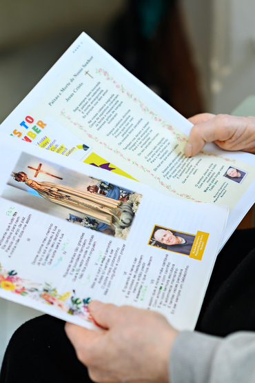 Joao holding prayers in the Village newsletter