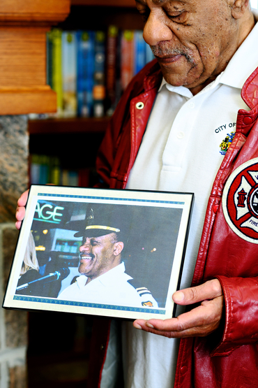 Ron Jones holding an old photo of him as a fireman