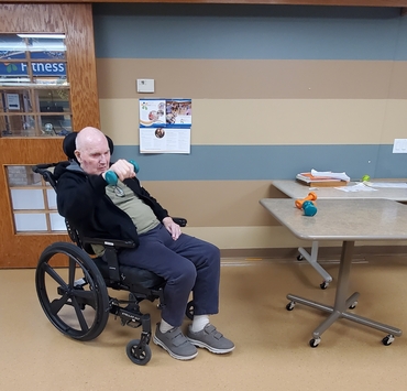 David lifts small weights in the fitness room while seated in his wheelchair. 
