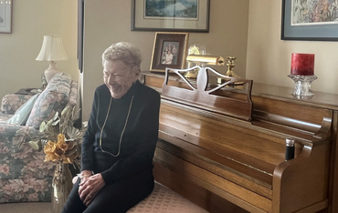 Lou sits before her beloved piano in her suite, in mid-laughter. 