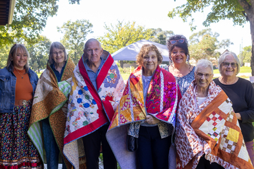 Schlegel Villages residents stand alongside members of The Six Nations on the Grand River wrapped in quilts that were gifted to the Villages.