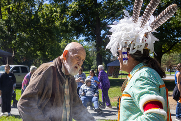A Schlegel Villages resident shares conversation with a member of The Six Nation on The Grand River who is dressed in traditional attire.
