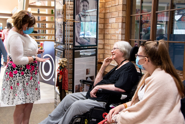 Guest chatting with residents who sits beside her photo in the exhibit