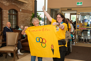 Riverside Glen residents carrying their Village flag into the Schlegel Olympics