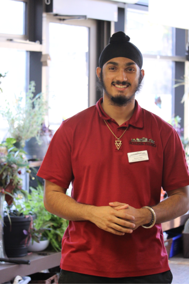 Taranjot stands along Main Street in the Village, smiling wide in his red work shirt. 