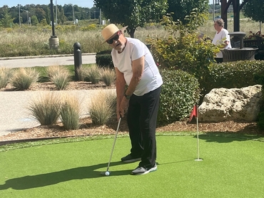 Walter, a resident at University Gates, prepares to make a putt on the Village's putting green. 