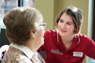 A team member speaks with a resident at the dining room table. 