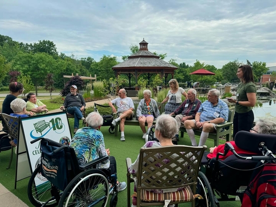 A large group gathers around the Green Bench to celebrate 10 years of the ElderWisdom campaign.