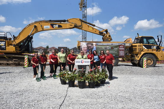 The Coleman Team stands in front of the excavators at the site of their new home, The Village of Innis Landing.