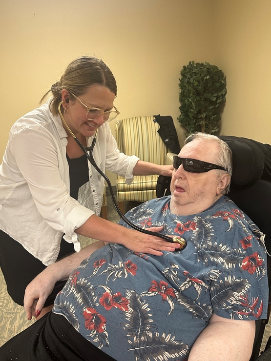 Christine listens to a resident's heart rate with a stethoscope - as a nurse practitioner she has many points of contact with residents.