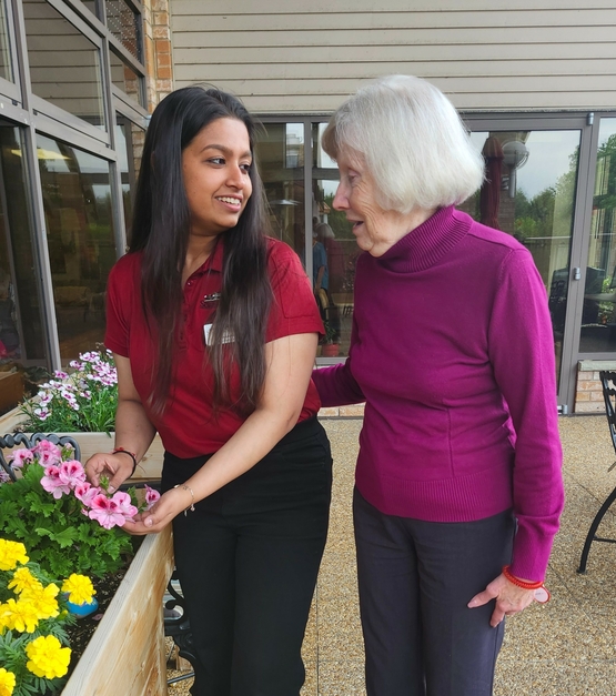 Devanshi and a Riverside Glen resident chat by a flower garden. Sometimes connecting over something simple, like a shared love of gardening, can open the path to new connection. 