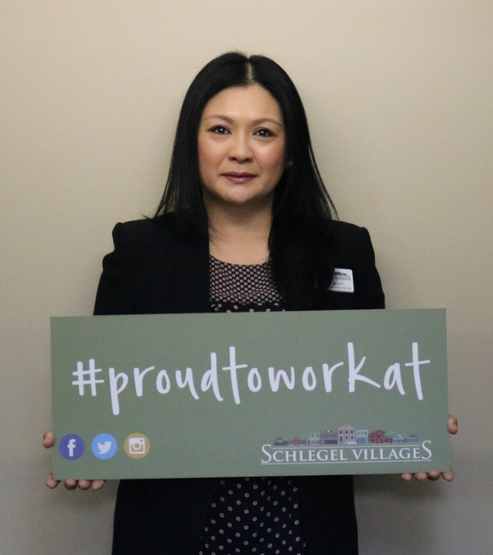 Ridgeview Court General Manager, Donna Dalupan, is holding a sign that reads "Proud to Work At." She was instrumental in the success of the pilot enhanced supportive neighbourhood at Erin Mills Lodge.