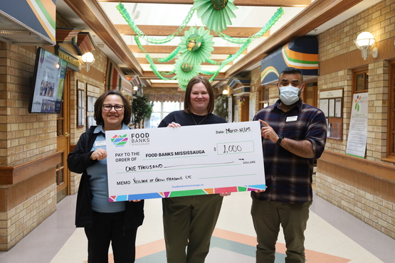 Erin Meadows team members Sami Kermani and Terence Paul stand alongside Stacey Kelly with the Village's $1,000 donation.