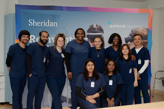 Sheridan College's PSW students are the first cohort to study at the new Living Classroom at Erin Meadows. The students pose together in front of a Sheridan College banner.