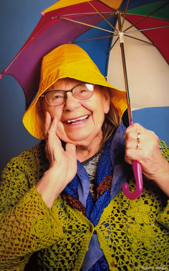 Freda is pictured smiling with a colourful rainhat and umbrella.