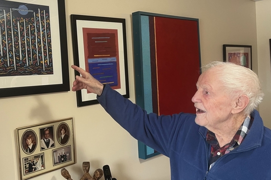 George in his suite at Arbour Trails, points out the colouring in one of his paintings.