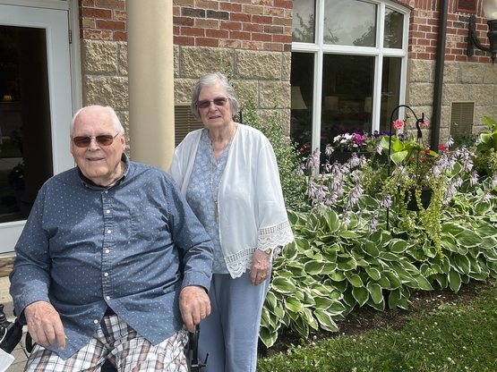 Art and Betty stand outside of their Arbour Trails suite in front of their lovely garden. 