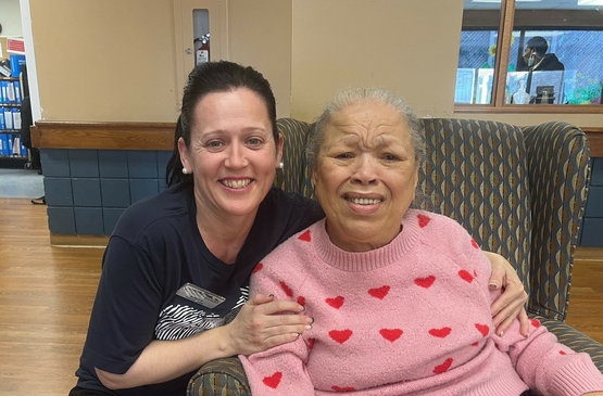 Windy poses with her arms around one of the residents she supports in the Elliott neighbourhood at The Village of Sandalwood Park.