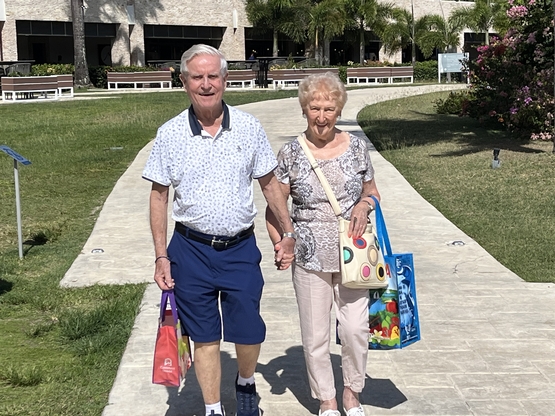 Don and Esme walk hand-in-hand along a path in their Antigua resort. 