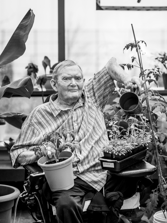 Jack Sutton black and white portrait in the greenhouse watering the plants