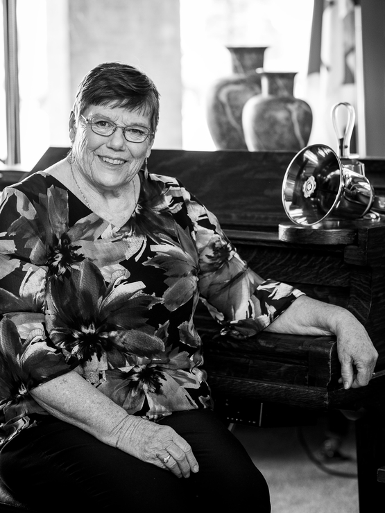 Kathryn Wall black and white portrait at the piano and and bells on display