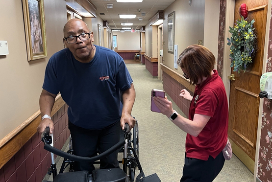Tracey dances as Kelvin walks to the music off her phone. 
