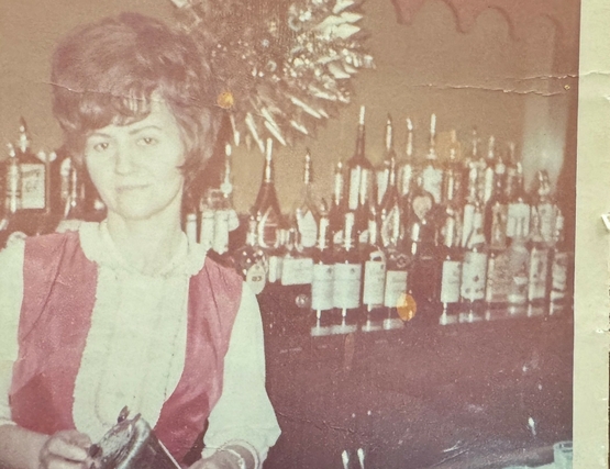 Lena serves drinks from behind the bar at the hotel she once owned and operated. 