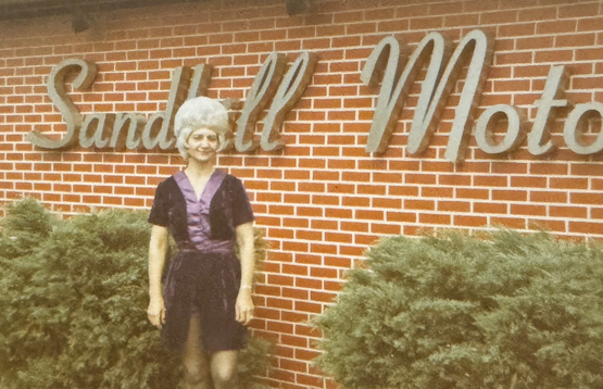 Lena stands before the sign for the Sandhill Motor Hotel she owned and operated. 